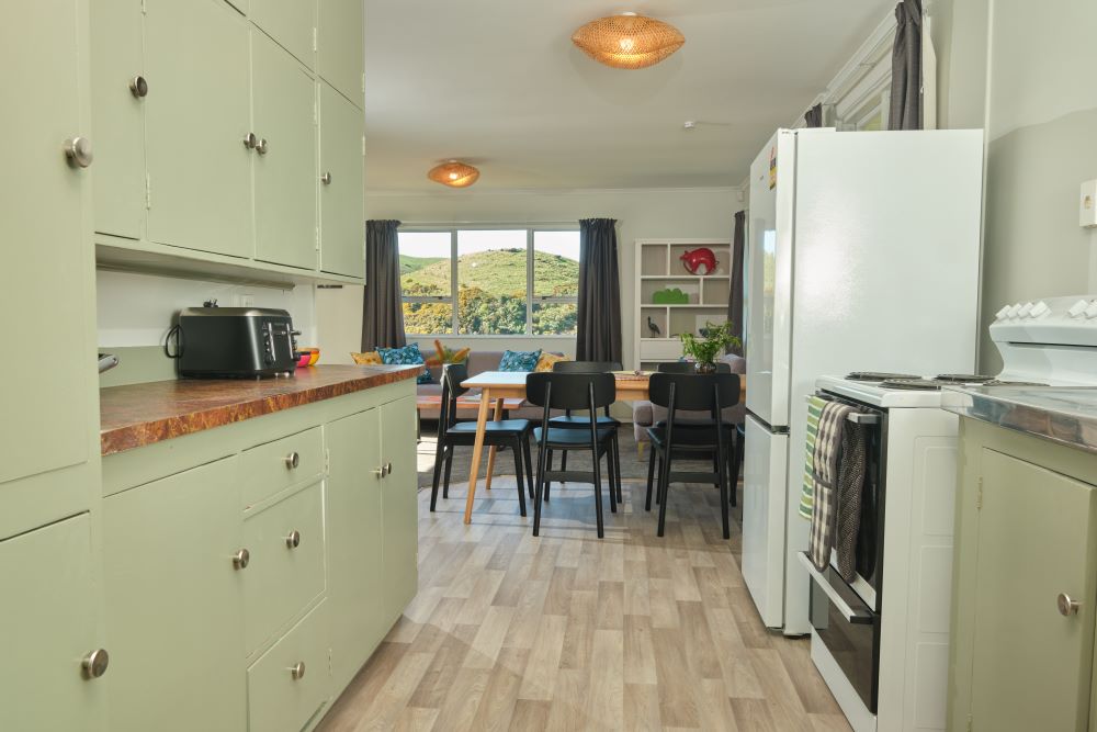 A shot of the house's kitchen, with an oven, fridge, toaster, and pale green cupboards