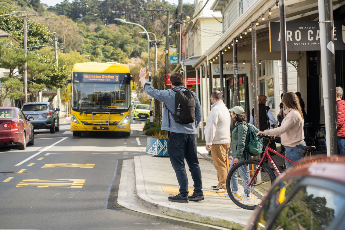 A man hails down a bus on a city street