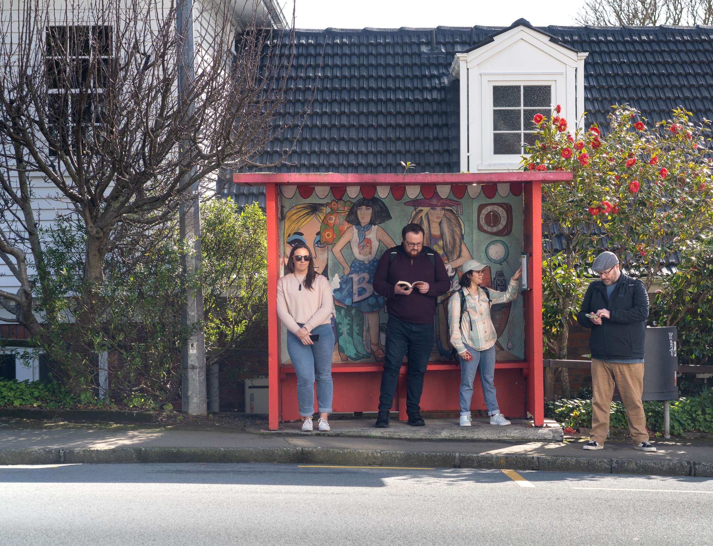 A group of people stand and wait at a bus stop